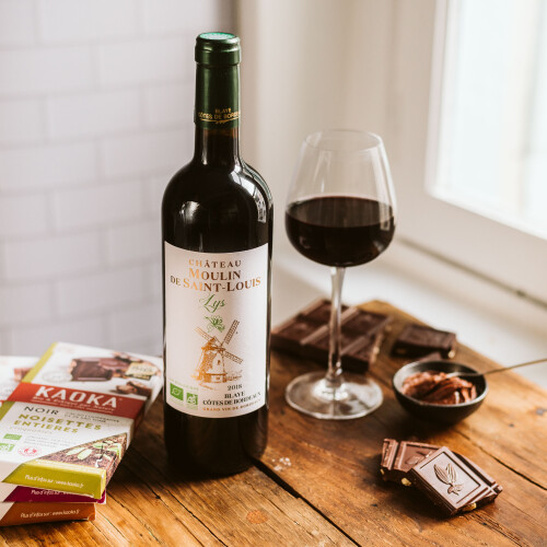 A bottle and glass of Bordeaux's Chateau Saint Louis red wine surrounded with luxury chocolates
